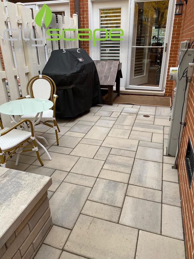 Gold Coast stone patio with a covered grill, round table, chairs, and sliding glass doors beside a brick wall