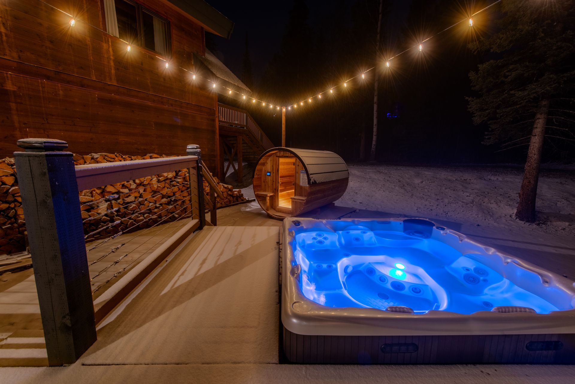 A hot tub and a sauna are on a deck at night.