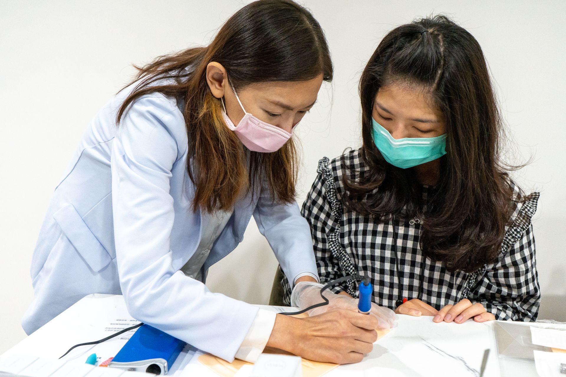 兩名戴著面具的女子坐在一張桌子旁。