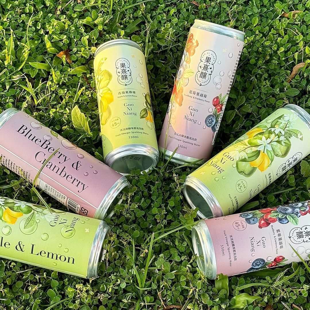 六個色彩鮮豔的飲料罐圍成一個圓圈擺放在綠草地上。