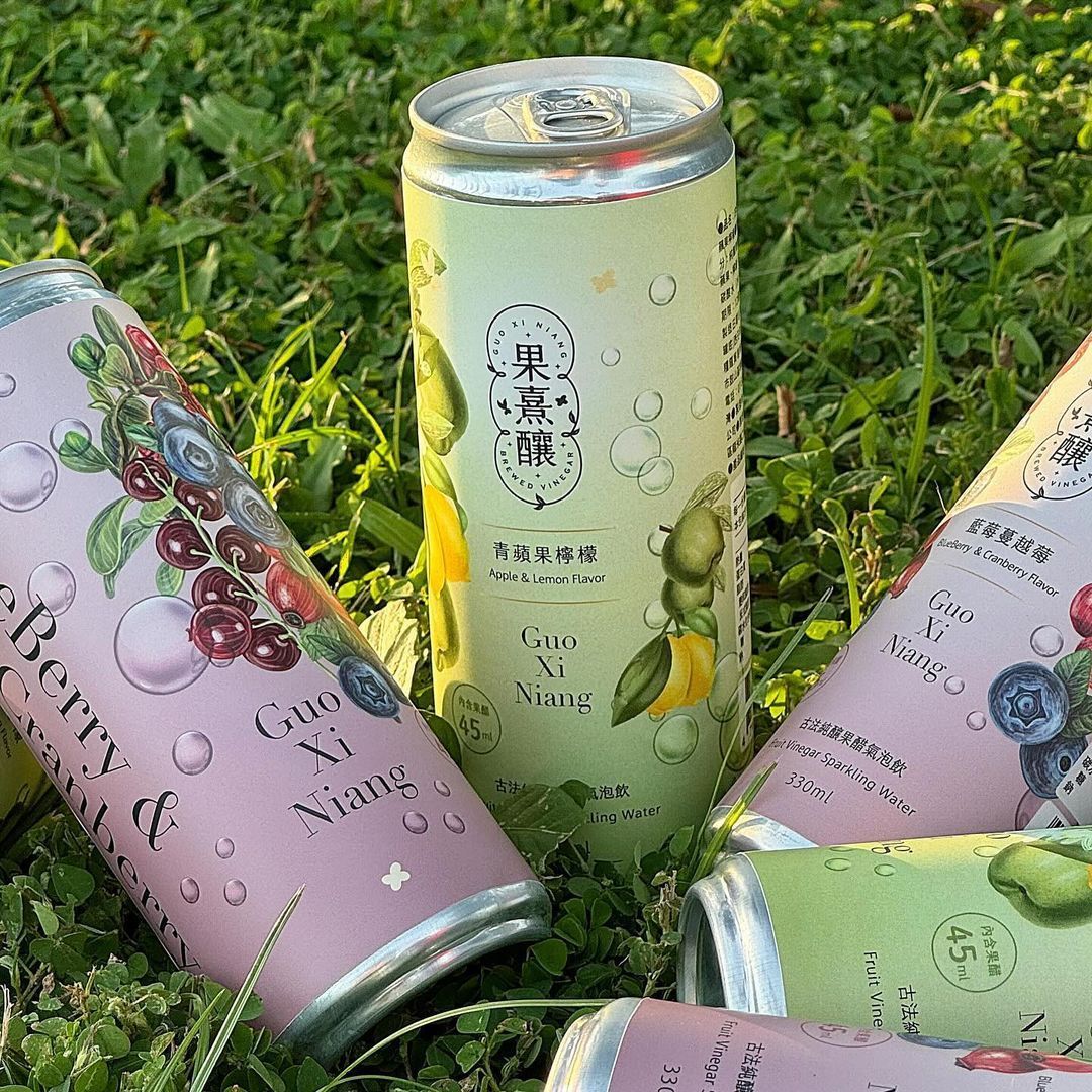 各種口味的罐裝果汁飲料散落在綠草地上。