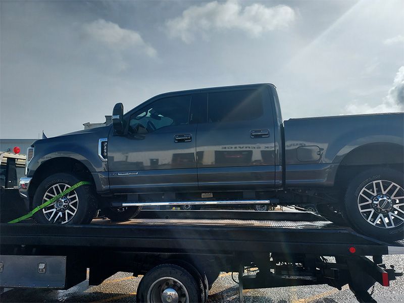 A gray truck is sitting on top of a tow truck.
