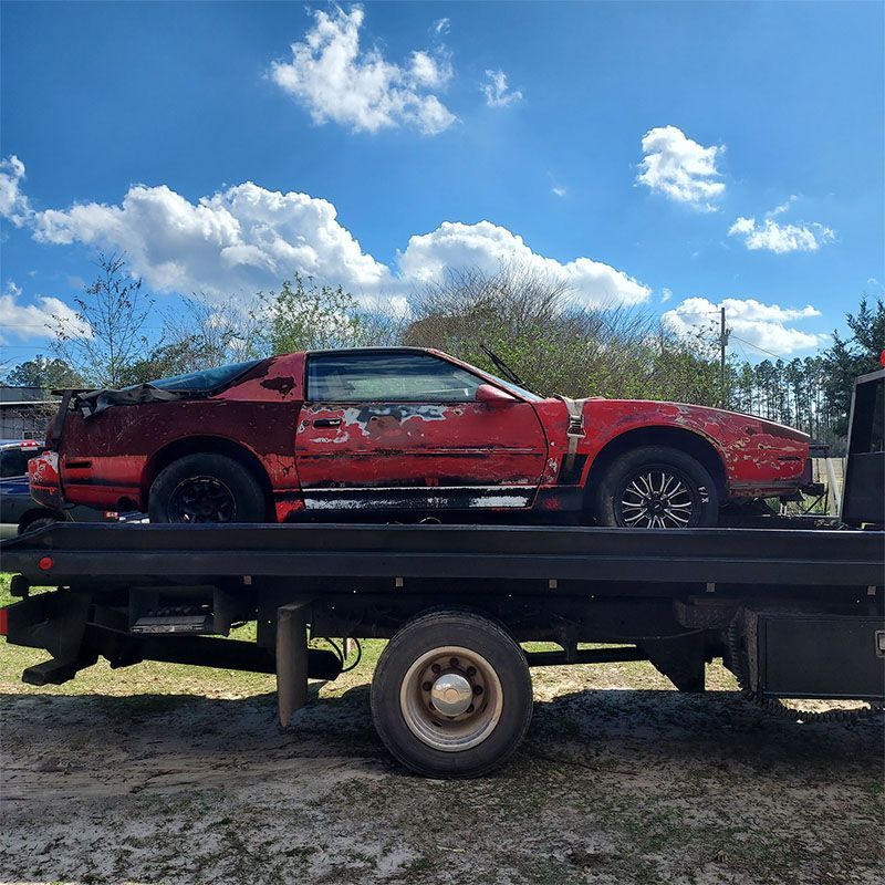 A red car is sitting on top of a tow truck.
