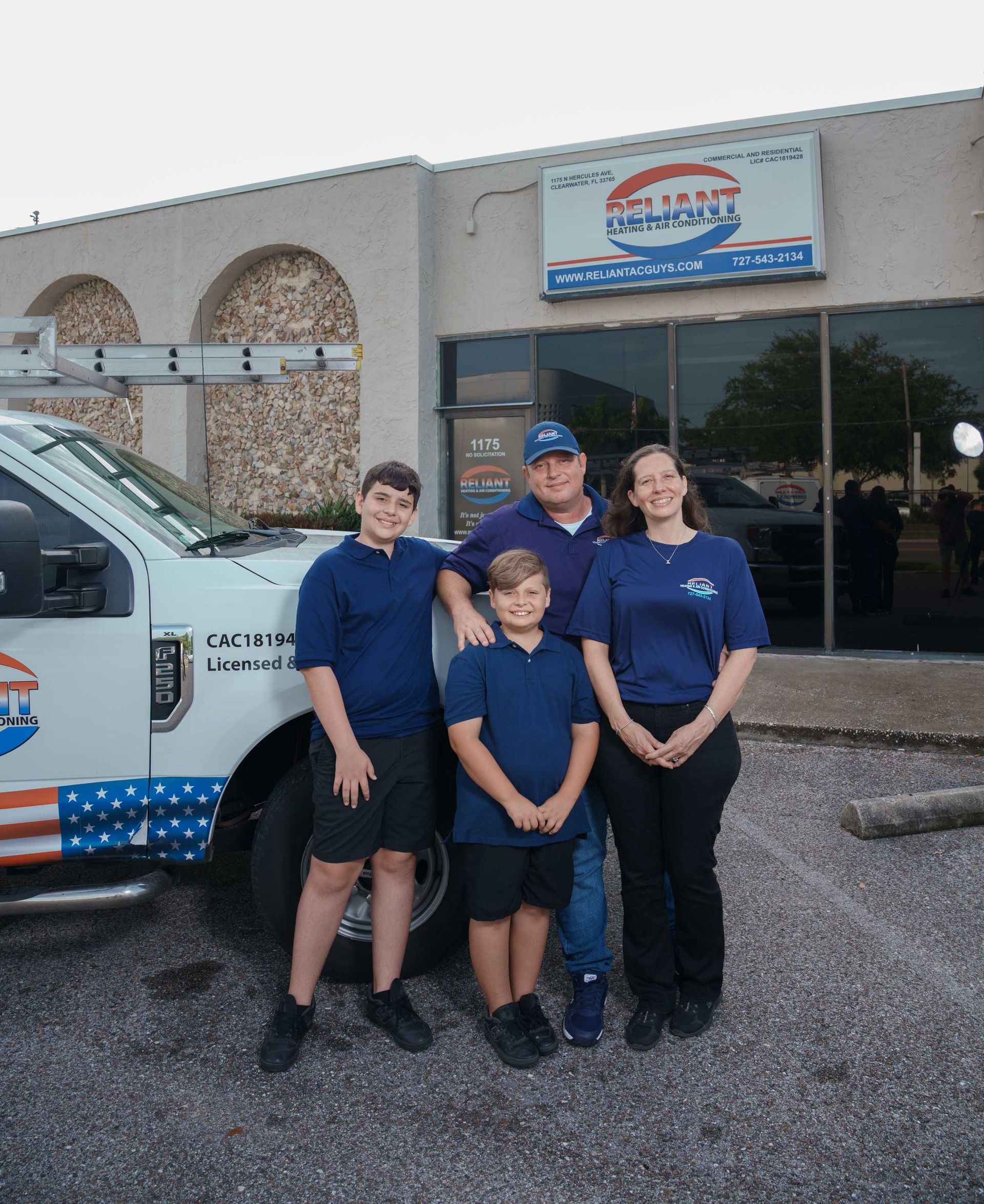 Reliant Heating & Air Conditioning family is posing for a picture in front of a truck.