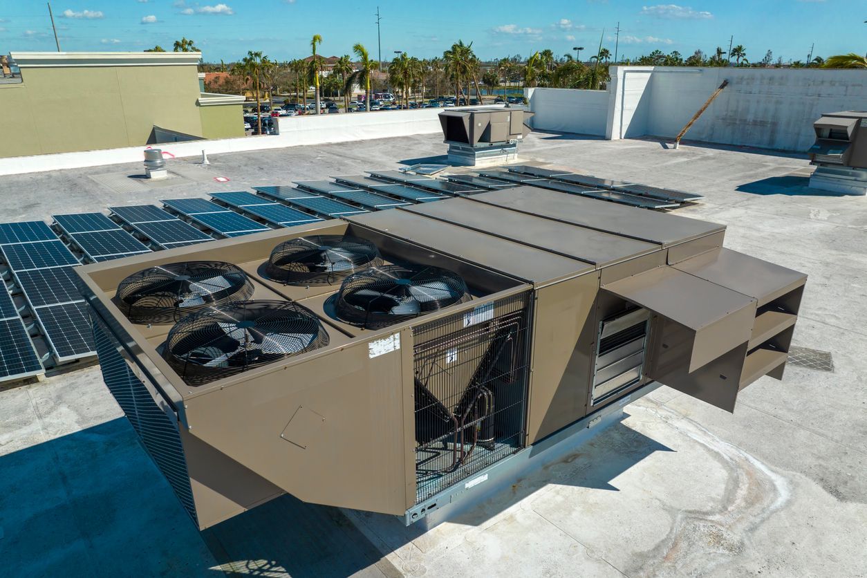 A large air conditioner is sitting on top of a roof next to solar panels Installed by Reliant Heating & Air Conditioning.