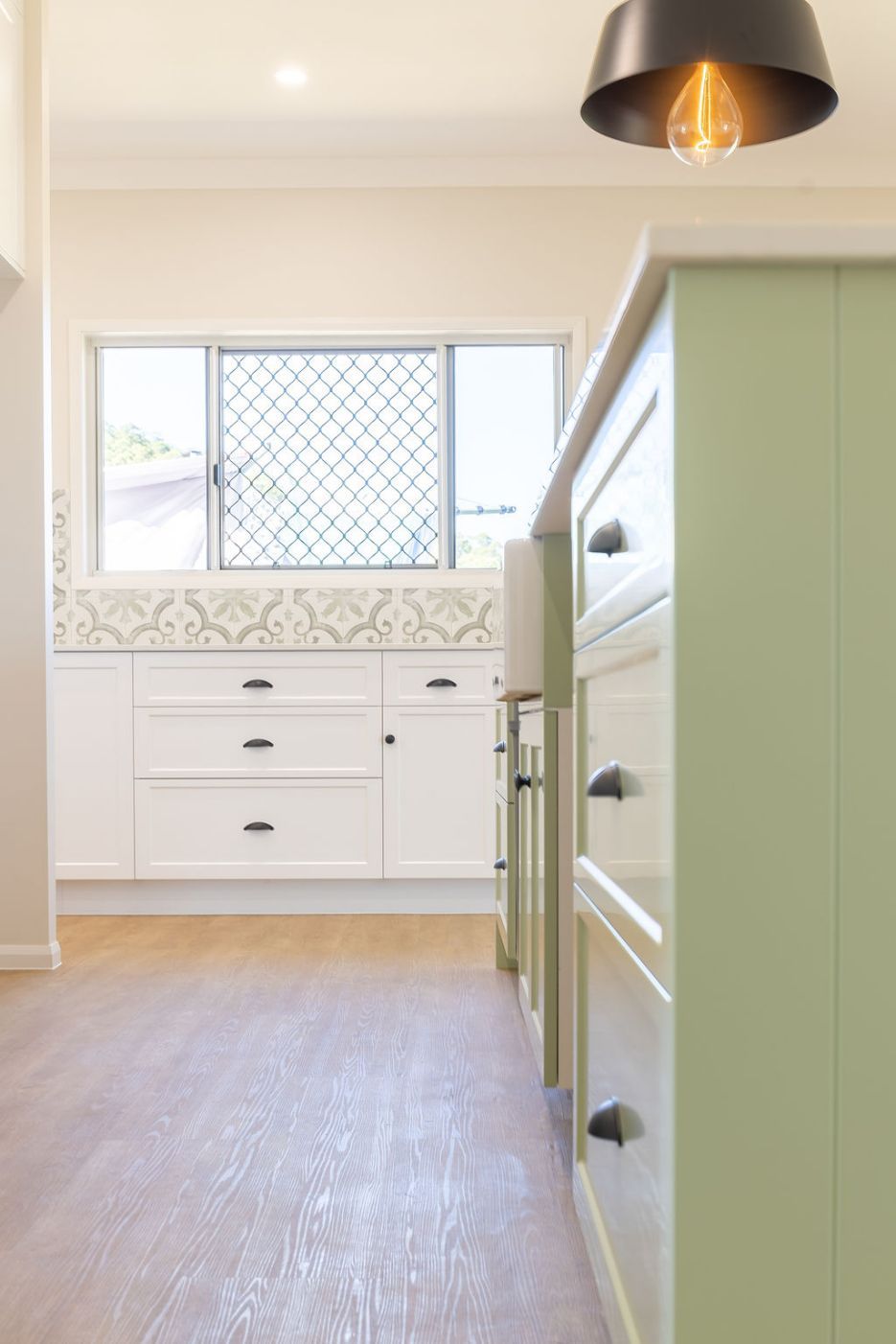 Light green kitchen cabinets with black hardware — Vaughan Building Group in Yeppoon, QLD