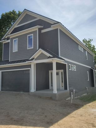Two-story house with gray siding, white trim, a dark garage door, and a small front porch.