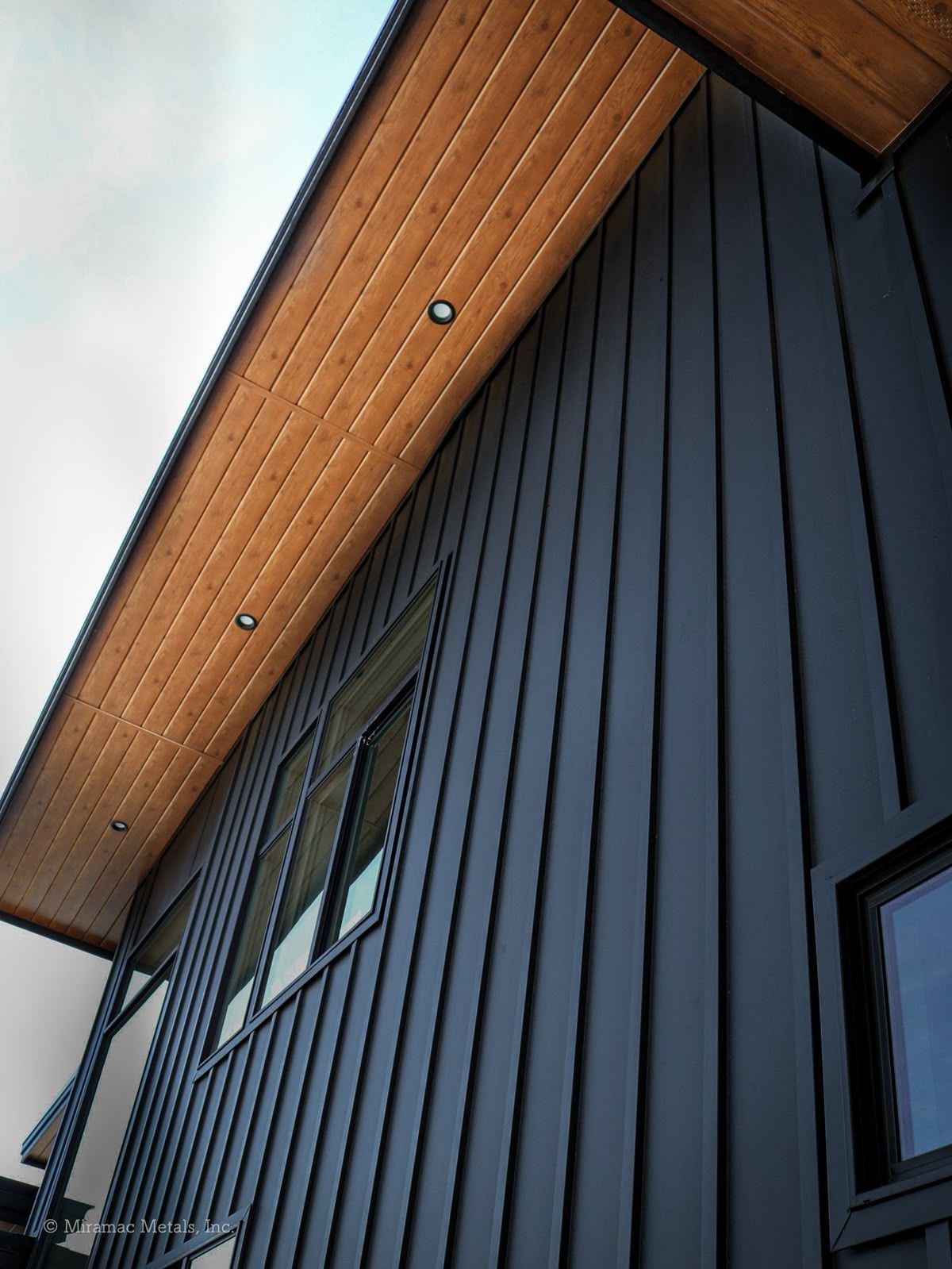 Dark blue building exterior with wood paneling and soffit, windows.
