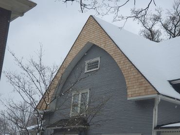 Gray house with arched roof, snow-covered, winter scene.