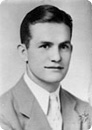 Black-and-white portrait of a man in a suit and tie, facing the camera with a slight smile.