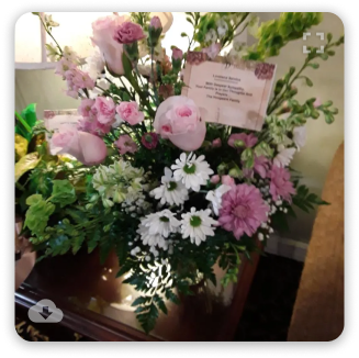 Pink and white floral arrangement with a small note card on a table