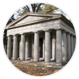 Stone memorial temple with tall columns and autumn leaves on the ground