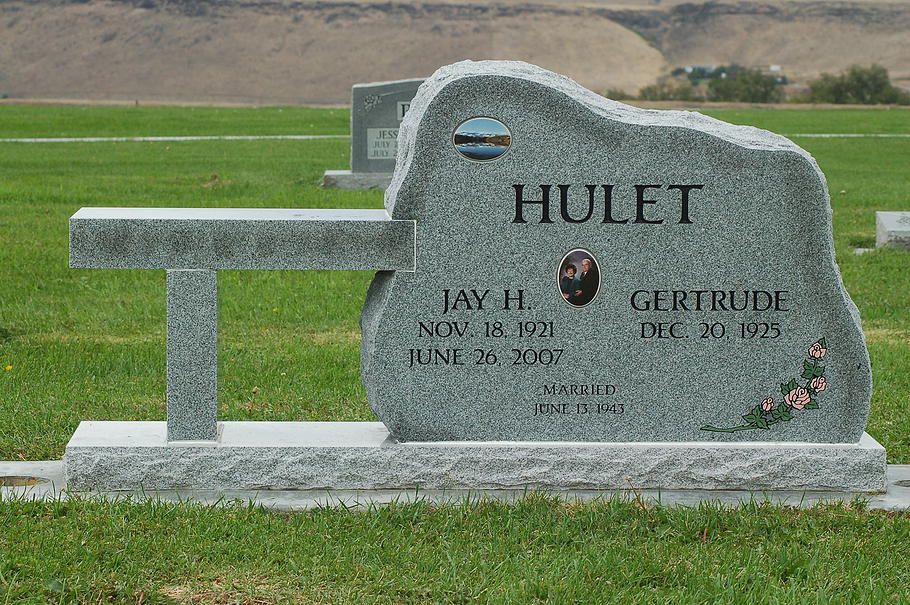 Gray Hulett gravestone with bench in a grassy cemetery