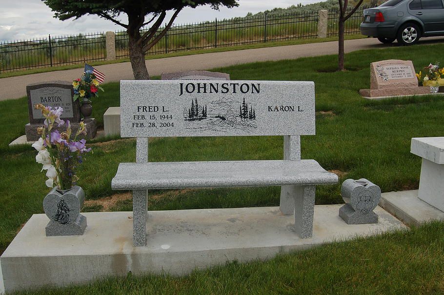 Johnston family gravestone with bench in a grassy cemetery, decorated with flowers