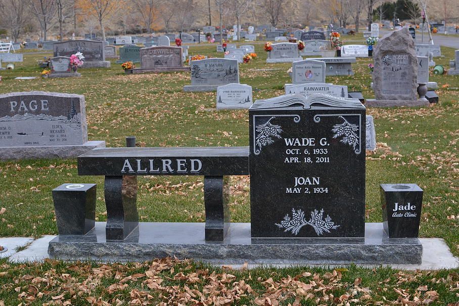 Cemetery with black and gray gravestones and a black memorial bench marked ALLRED.