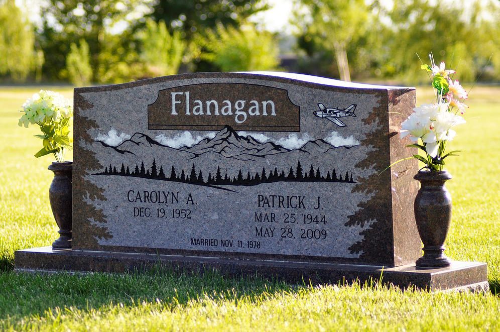Flanagan family gravestone with engraved names and floral vases in a sunny cemetery