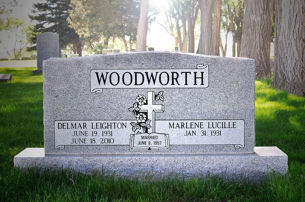 Woodworth family gravestone in a cemetery, with engraved cross and flowers in the background