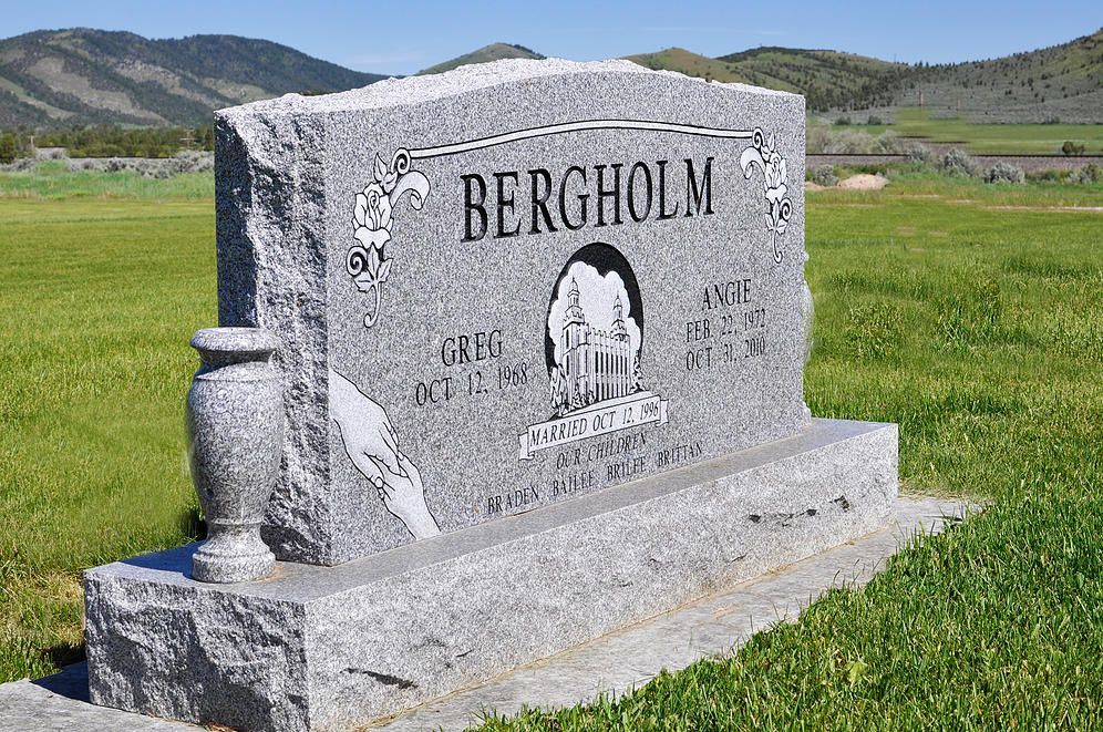 Granite grave marker engraved “BERGHOLM” in a green cemetery with hills in the background
