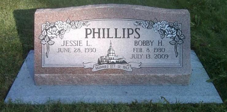 Granite memorial headstone with engraved names and dates, set on a concrete base in grass