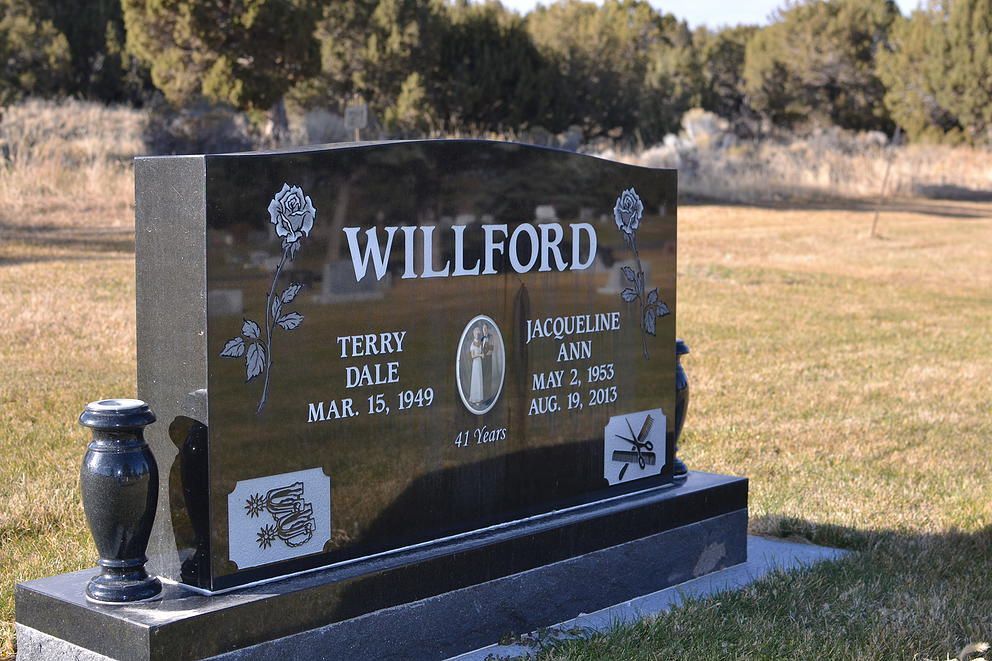 Black granite Willford gravestone in a grassy cemetery with trees in the background