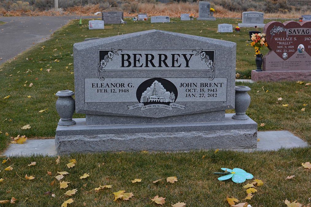Gray BERREY gravestone in a cemetery with flowers and autumn leaves on the grass