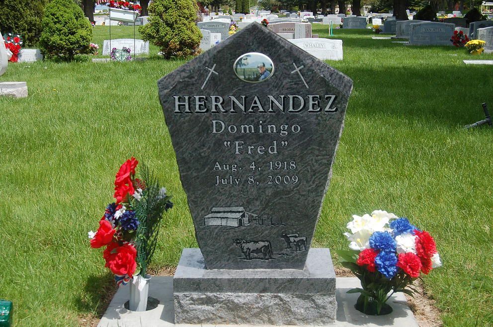 Gravestone in a cemetery with red, white, and blue floral arrangements on both sides