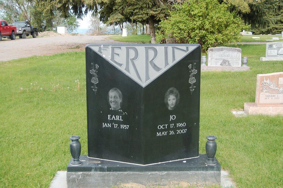 Black granite gravestone in a cemetery with two portrait photos and “MERRI” at the top.
