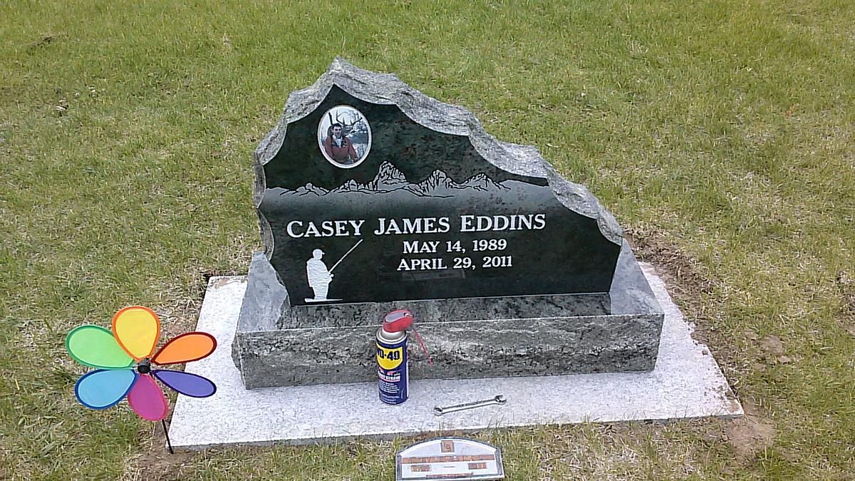 Memorial gravestone on grass with flowers and a small candle in front