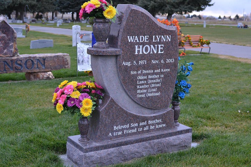 Marble grave marker with flower vases in a cemetery, inscribed “WADE INN HONE.”