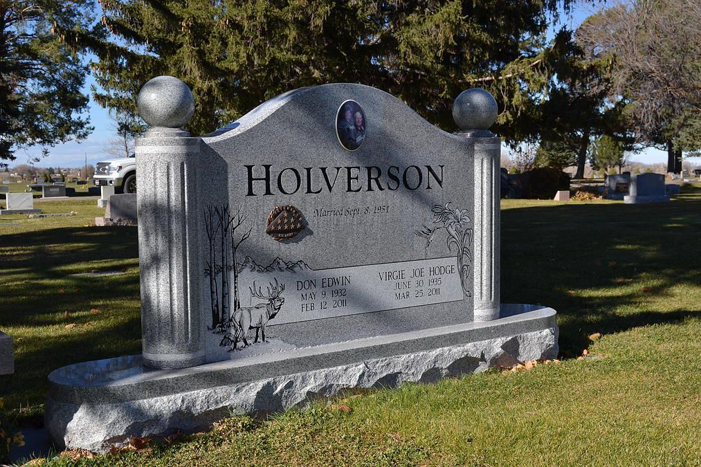 Gray granite gravestone with “HOLYERSON” engraved, set on a grassy cemetery lawn under trees.
