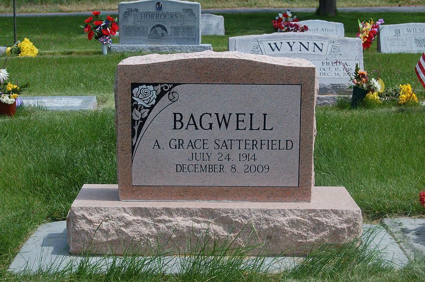 Gravestone for Grace Sheffield Bagwell in a cemetery, with flowers and other headstones behind it.