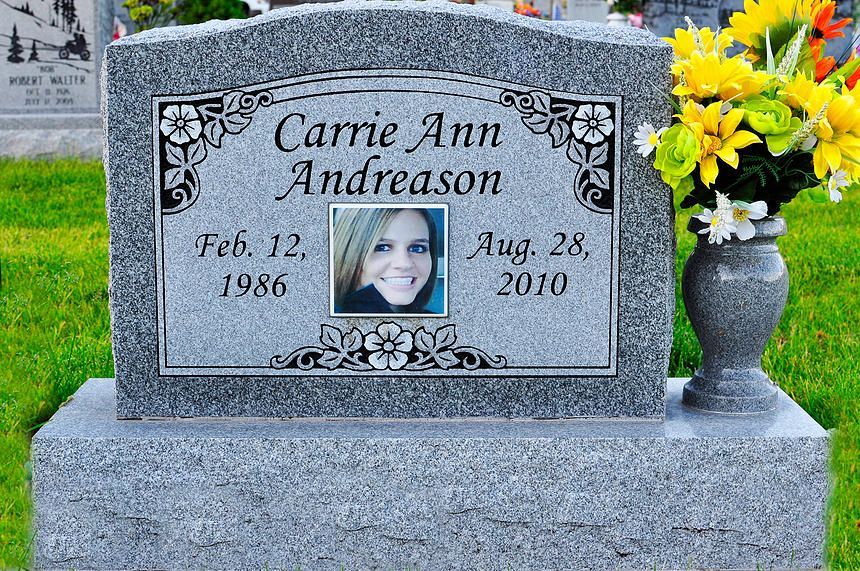 Gravestone for Carrie Ann Andreason with portrait, dates, and yellow flowers in a vase