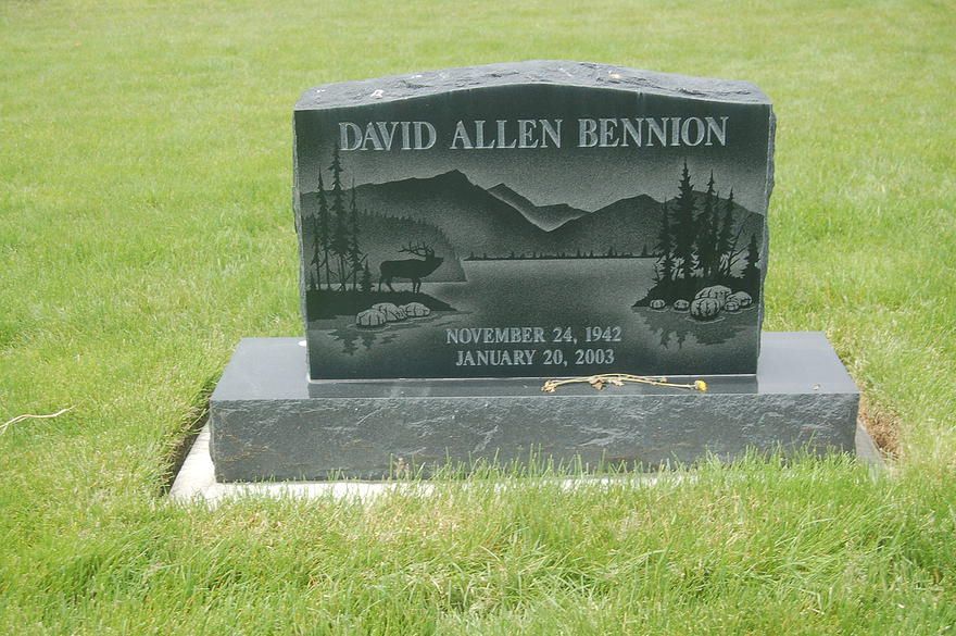 Gray gravestone in a grassy cemetery engraved “David Allen Bennion” with dates and military imagery.