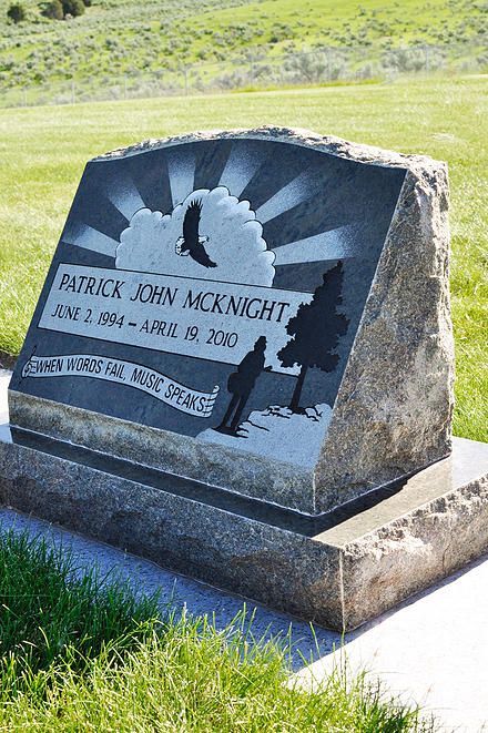 Black memorial gravestone with eagle silhouette in a grassy cemetery