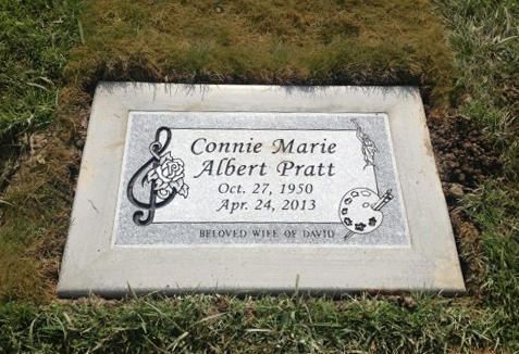 Gravestone plaque for Connie Marie Albert Pratt with treble clef and angel designs on grass