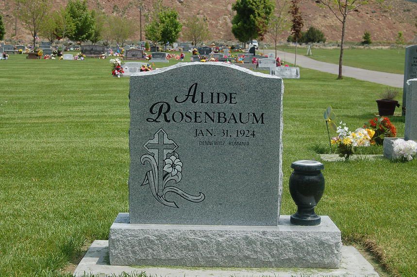 Gray granite gravestone in a cemetery, engraved with the name Aude Rosenbaum and a vase beside it.
