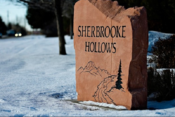 Sherbrooke Hollows carved stone sign in snow beside a road