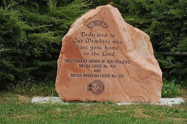Brown commemorative stone monument in grass, engraved with a memorial dedication plaque.