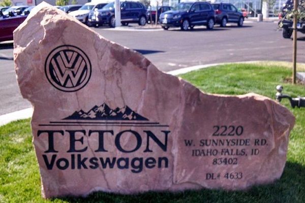 Teton Volkswagen dealership sign on a large pink stone by a roadside parking lot