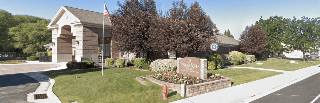 Suburban townhouse entrance with landscaped sign, manicured lawn, trees, and a curved road