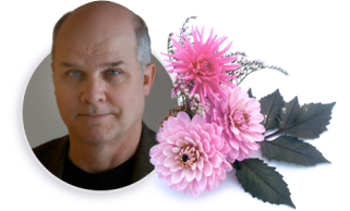 Portrait of a bald man beside pink flowers and gray-green leaves on a white background