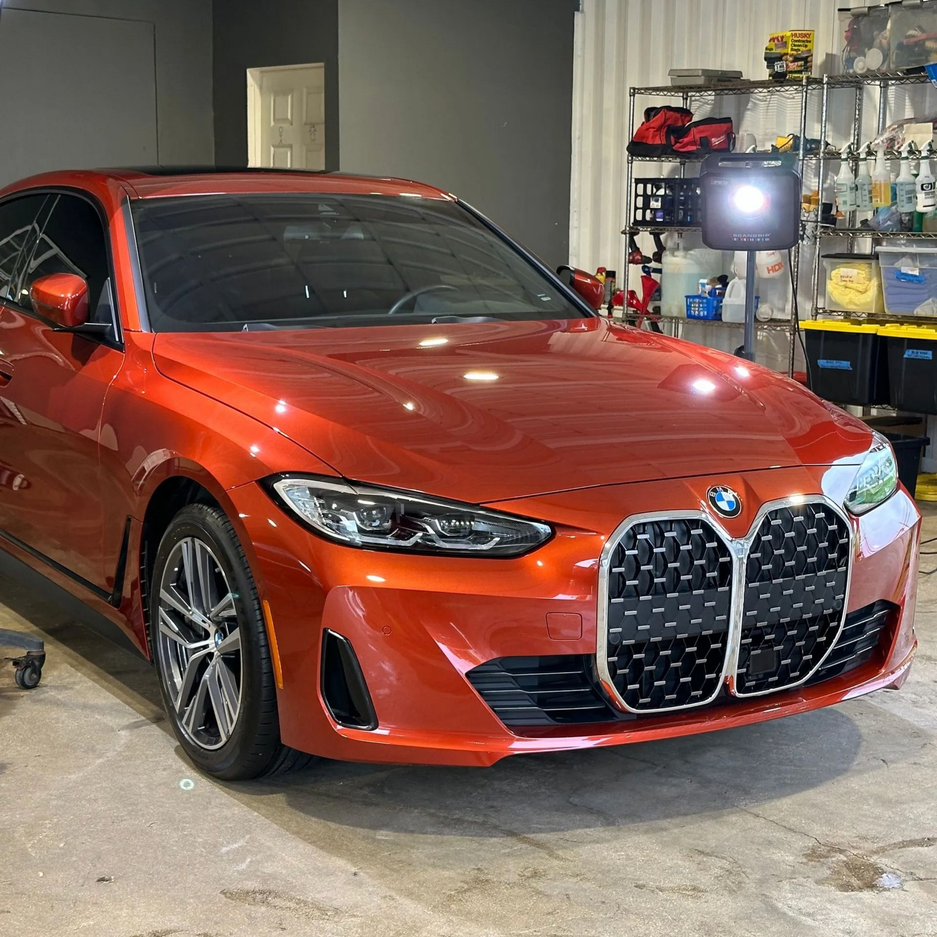 A person is cleaning a blue car with an orange towel
