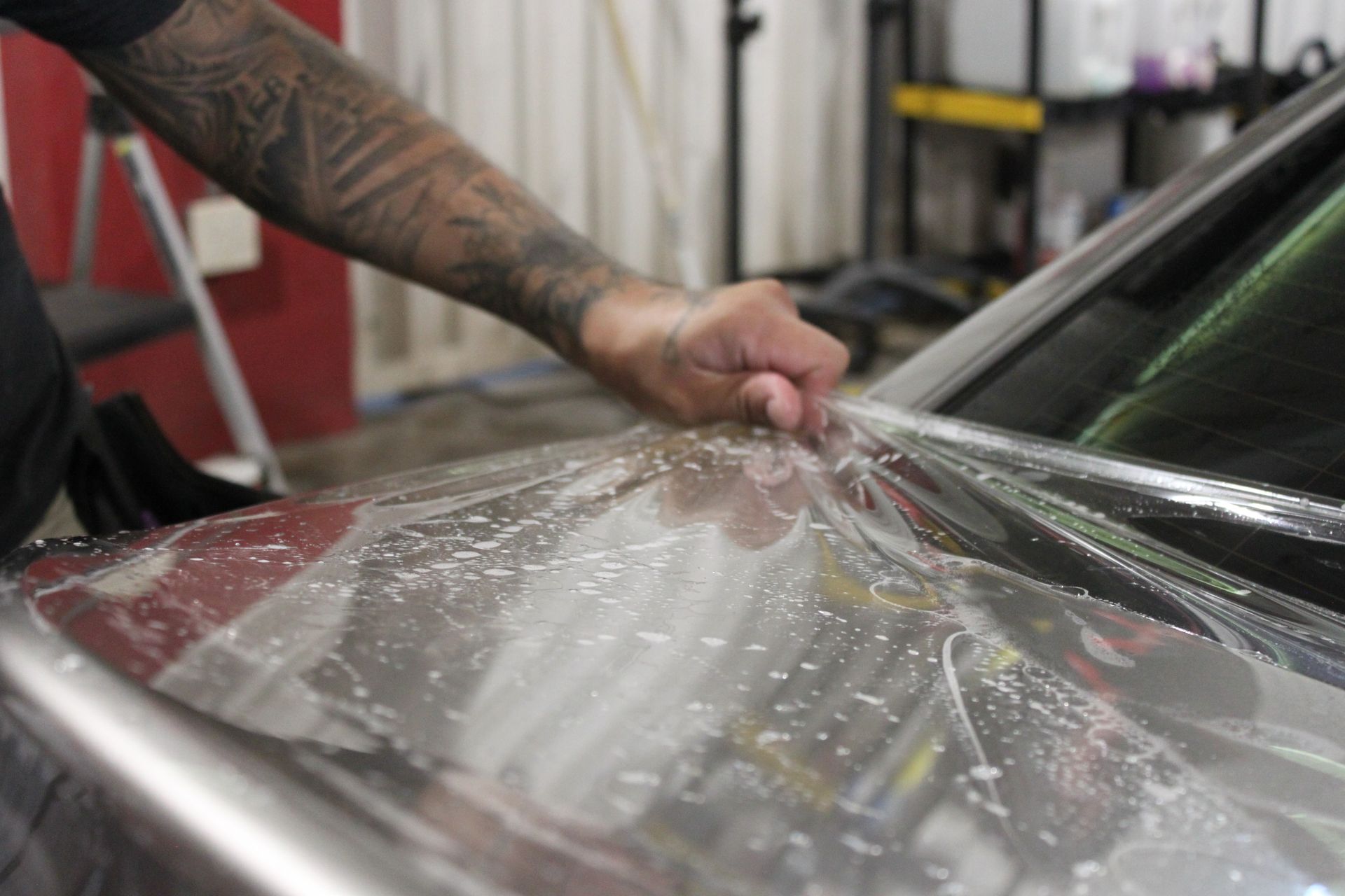 A person is applying tinted glass to a car windshield.