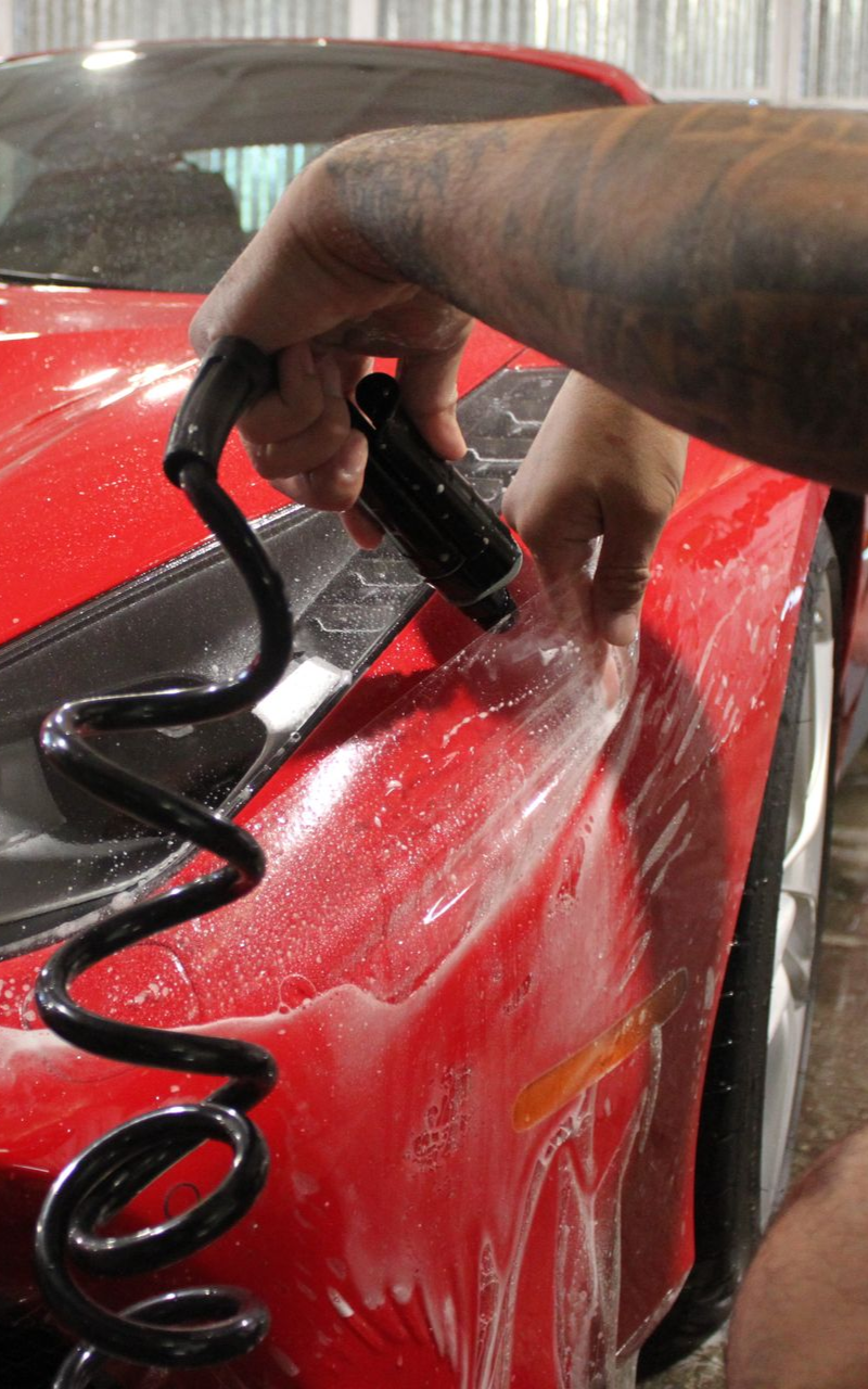 A silver car is being washed with soap and water