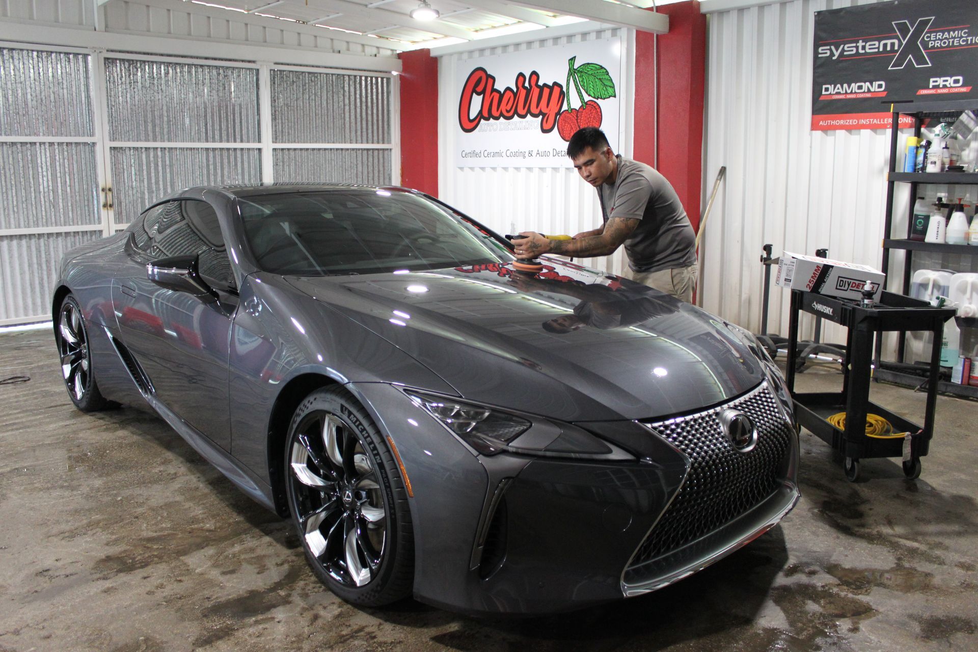 A person is cleaning a blue car with an orange towel