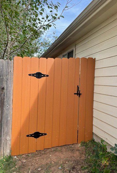 Orange wooden gate with black hinges and latch.