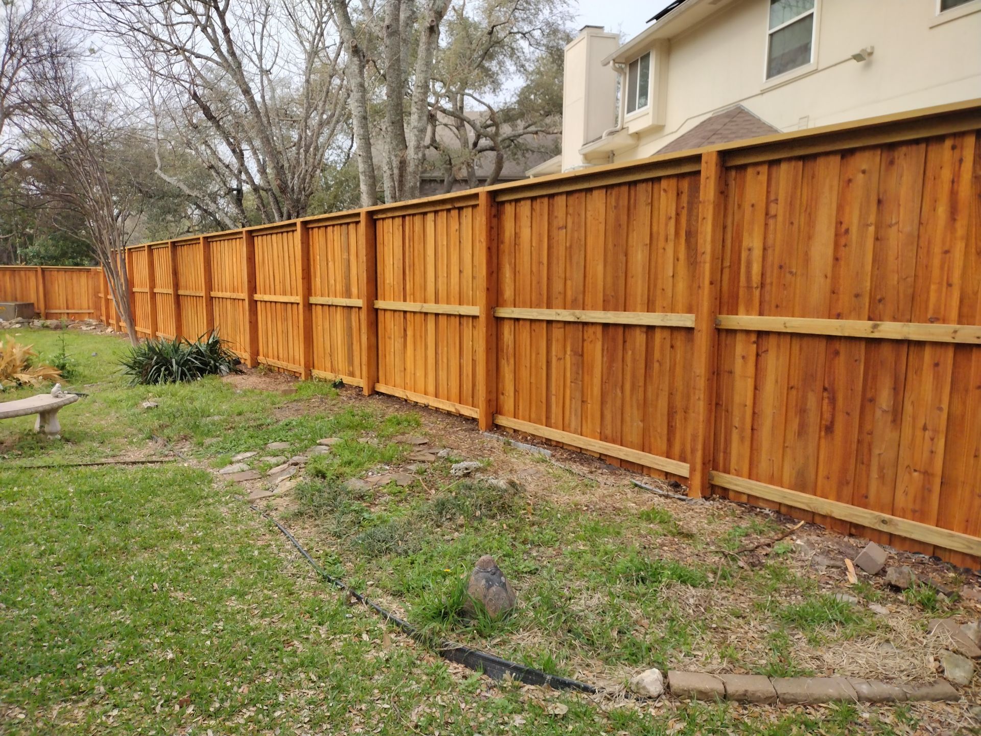 Wooden privacy fence in a grassy backyard.