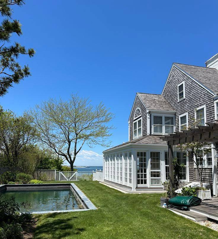 Beachside house with pool, green lawn, and blue sky
