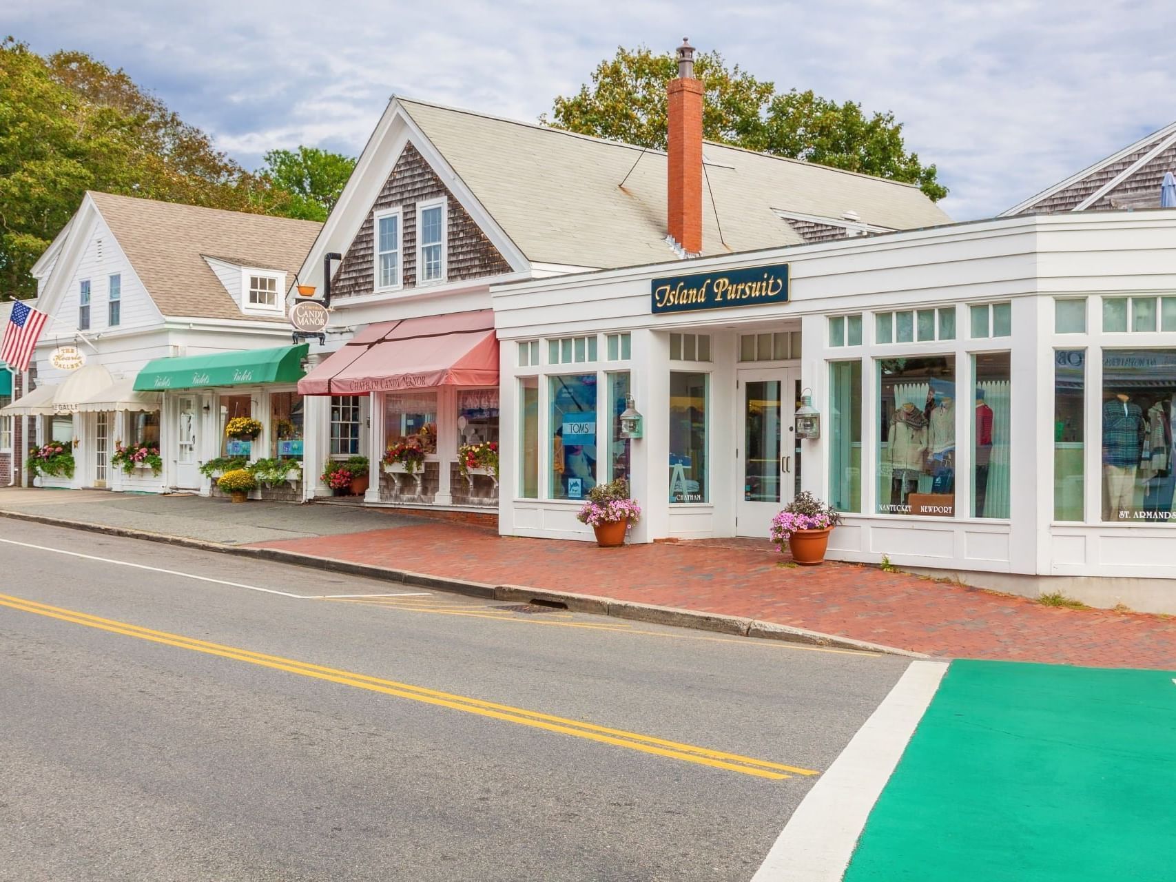 Small shops with colorful awnings along a quiet street, with a white storefront and red brick sidewalk