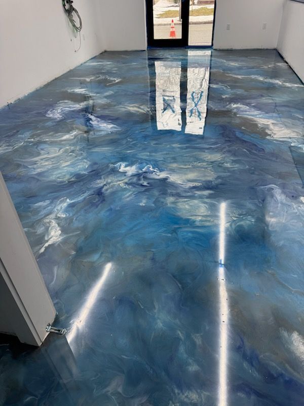 Empty room with glossy blue marbled epoxy floor and reflections of overhead lights.